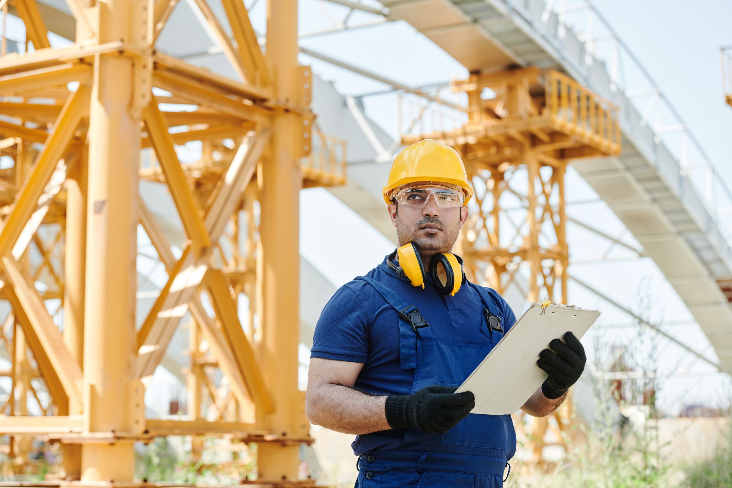 Site engineer reviewing work beside construction equipment